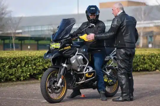 A person offers guidance on slow speed skills to a motorcyclist